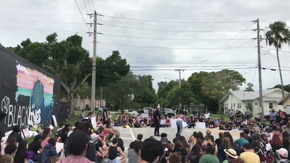 Protesters have gathered in front of a mural on 23rd Street and are listening to individual speakers from the crowd.