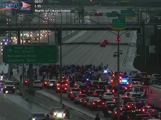 Hundreds of people gathered at an I-95 overpass near Okeechobee Boulevard in West Palm Beach to voice their support for the Cuban people amid protests on the island nation. 