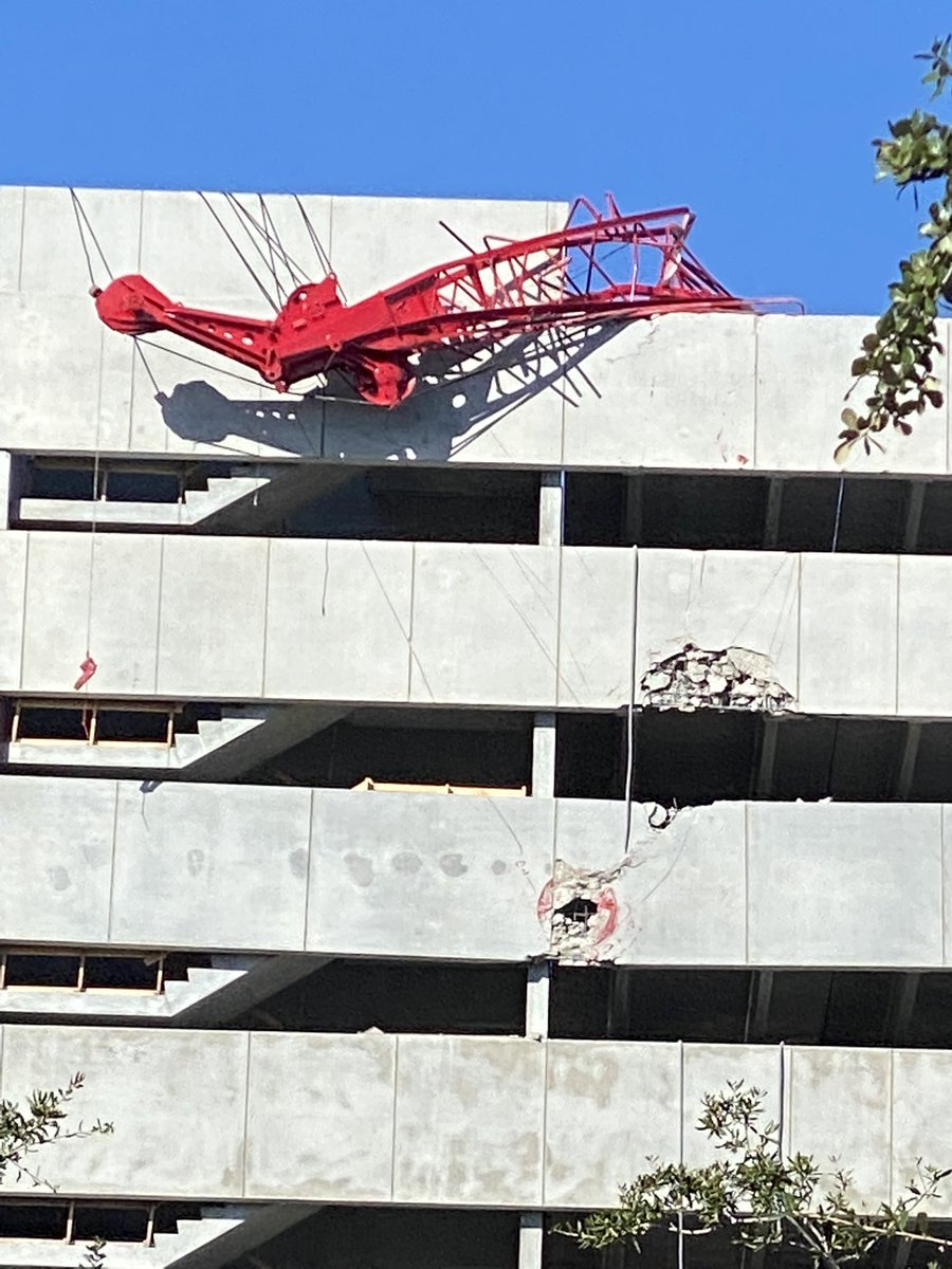A piece of construction equipment is hanging over the side of a new parking garage that is part of the extended @AdventHealth campus off of Smith Street.  