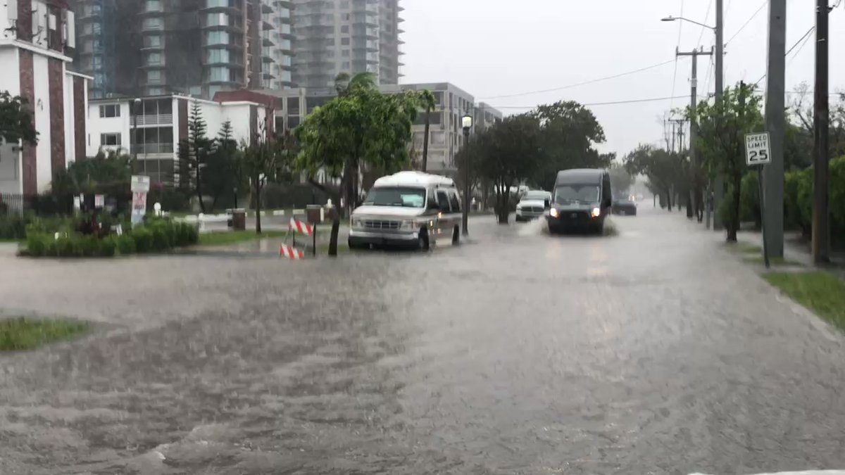 Larger vehicles are getting through the flooded street but small cars are turning around or avoiding this part of N Flagler