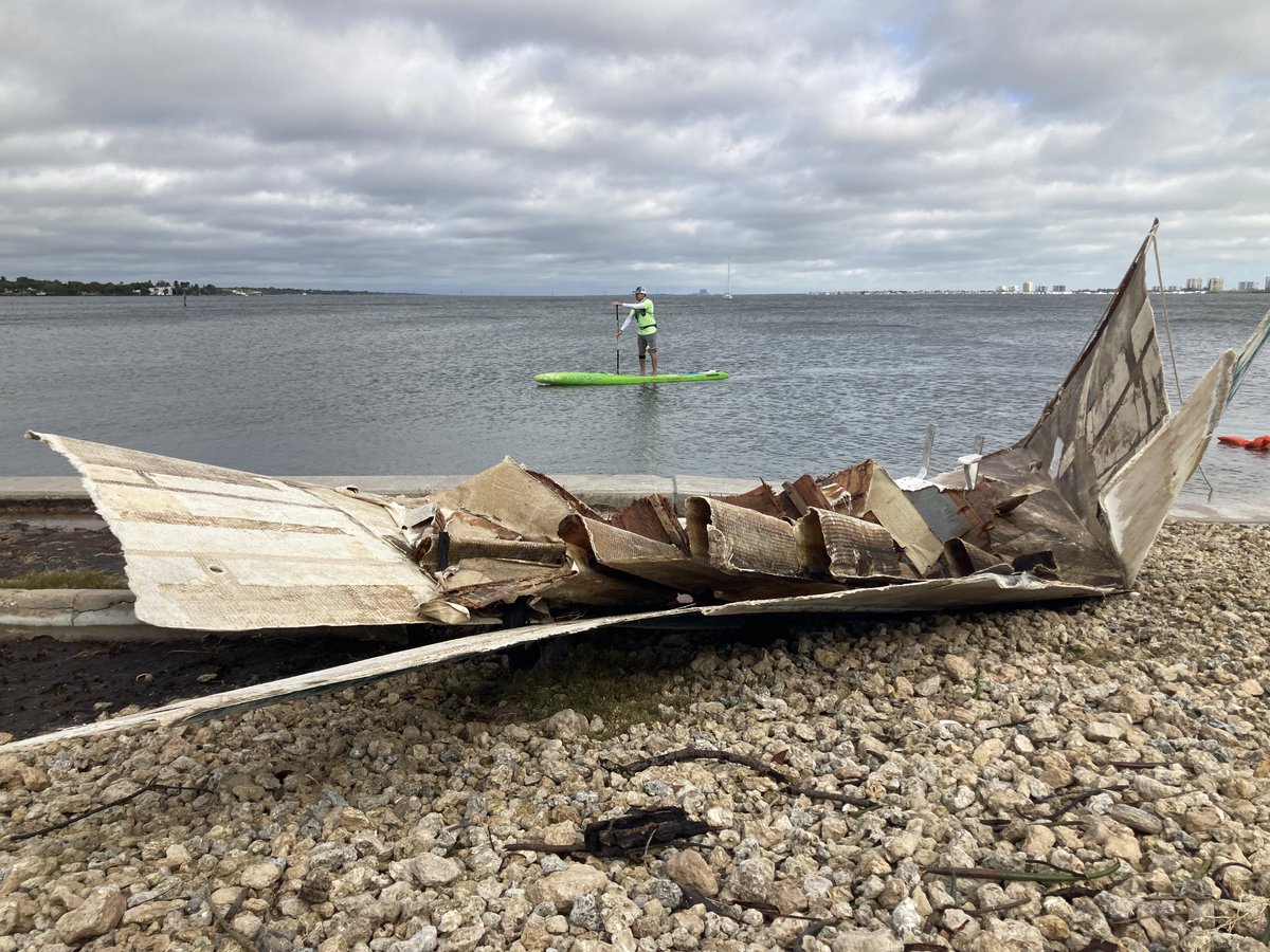 Paddle boarder makes his way past ripped apart boat at Jensen Beach Causeway in Martin County